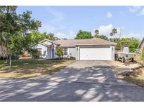Charming single-story home with a well-maintained lawn and a two-car garage with a boat to the side at 2713 Needle Palm Dr, Edgewater, FL 32141