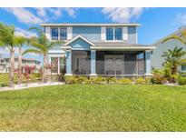 Charming blue two-story home with a screened-in porch, lush landscaping, and a well-manicured lawn at 3136 Portofino Blvd, New Smyrna Beach, FL 32168