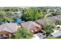 Aerial view of a two-story home with an orange exterior and an attached two-car garage near a lake at 3311 Pine Oak Trl, Sanford, FL 32773