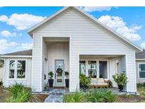 Charming home featuring a covered porch, light blue door, beautifully landscaped front yard and striking architectural details at 6542 Rover Way, St Cloud, FL 34771