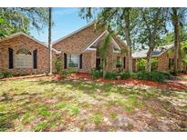 Charming single-story brick home with arched windows, lush landscaping, and mature trees at 682 Ferncliff Dr, Port Orange, FL 32127