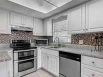 Bright kitchen features white cabinets, stainless appliances, granite counters, and stylish tile backsplash at 95 Moonstone Ct, Port Orange, FL 32129