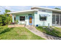 Charming home featuring a quaint blue door, awning, and well-manicured lawn with a stepping-stone walkway at 114 Hickory St, New Smyrna Beach, FL 32168
