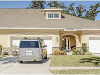 Charming beige home featuring an arched entryway, manicured lawn, and attached two-car garage on a sunny day at 1903 Turnbull Lakes Dr # 1903, New Smyrna Beach, FL 32168