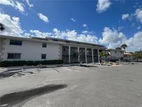 Multi-story condo with ample parking, manicured shrubs, and stately columns under a bright blue, cloudy sky at 2100 N Peninsula Ave # 2160, New Smyrna Beach, FL 32169