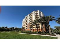 Multi-story condo building featuring multiple balconies surrounded by palm trees, tropical plants, and green lawns at 250 Minorca Beach Way # 206, New Smyrna Beach, FL 32169