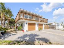 Two-story home features a double garage, a second-story patio and tropical landscaping at 2510 S Atlantic Ave, New Smyrna Beach, FL 32169