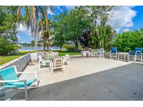 Large back patio with outdoor seating and mature tropical trees and bushes overlooking the water at 2576 Sunset Dr, New Smyrna Beach, FL 32168