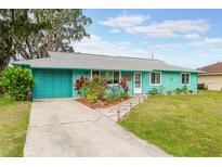 Charming turquoise home with a well-manicured lawn and colorful flower garden at 2726 Victory Palm Dr, Edgewater, FL 32141