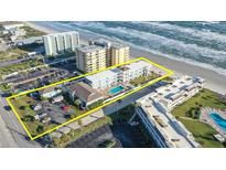 Aerial view of a beachside condo complex featuring a community pool, palm trees, and private beach access at 3509 S Atlantic Ave # 102 And 103, New Smyrna Beach, FL 32169