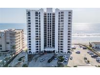 Condo building exterior with ample parking, blue signage, and ocean view from this multi-story condo at 3855 S Atlantic Ave # 1503, Daytona Beach Shores, FL 32118