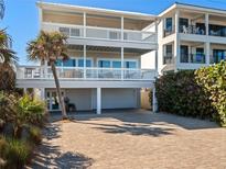 Coastal home featuring balconies, a paver driveway, and a convenient under-house garage for parking at 6530 S Atlantic Ave, New Smyrna Beach, FL 32169