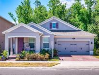 Charming single-Gathering home features a gray exterior, brick driveway, and inviting front porch with seating at 727 Porter Rye Ave, Debary, FL 32713