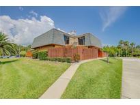 Two-story home with Mansard roof, green lawn, and balcony view, with a wooden fence, number sign, and walkway at 90 Cedar Dunes Dr, New Smyrna Beach, FL 32169