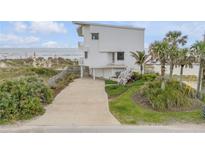 Stunning beachfront home featuring a multi-story design and inviting curb appeal with mature tropical landscaping at 951 N Atlantic Ave, New Smyrna Beach, FL 32169