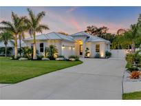 Beautiful exterior of a modern home with a well-manicured lawn, palm trees, and a concrete driveway at 102 Inlet Shores Dr, New Smyrna Beach, FL 32168
