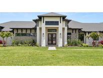 Beautifully landscaped home featuring stone accents and a covered entryway with a black double door at 1624 Turnbull Crossings Dr, New Smyrna Beach, FL 32168