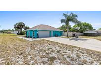 A quaint turquoise home featuring an attached garage, neat front yard, and a long driveway at 1845 Willow Oak Dr, Edgewater, FL 32141