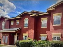 Two-story townhouse with red stucco exterior and manicured landscaping at 240 Villa Di Este Ter # 212, Lake Mary, FL 32746
