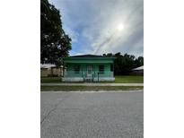 Charming one-story home featuring a porch, green exterior, and well-maintained yard at 306 Sheldon St, New Smyrna Beach, FL 32168