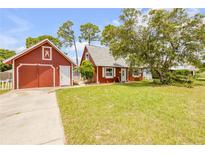 Charming red cottage with a detached garage and a well-maintained green lawn at 3222 Juniper Dr, Edgewater, FL 32141