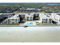 An aerial view of the Castle Reef Condominiums and the nearby beach, and community pool at 4175 S Atlantic Ave # 2280, New Smyrna Beach, FL 32169