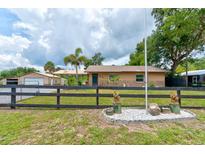 Ranch style home with neutral paint, black fence, and lush greenery at 130 N Gaines St, Oak Hill, FL 32759