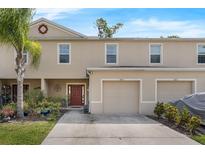 Tan two-story townhouse with well manicured landscaping, a neutral color scheme, and an attached single car garage at 1615 Primo Ct, Holly Hill, FL 32117