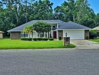 Charming brick home with a well-manicured lawn, mature trees, and a two-car garage at 1941 Spruce Creek Lndg, Port Orange, FL 32128