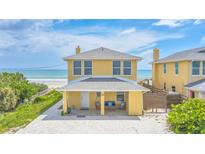 Charming yellow beach house with a covered front porch and ocean view at 2101 Hill St, New Smyrna Beach, FL 32169
