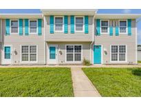 Inviting townhome featuring a tidy lawn, charming blue shutters, and a well-maintained facade at 2122 S Atlantic Ave # 2122, New Smyrna Beach, FL 32169