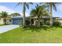 Charming single-story home with lush green lawn, colorful flowers, and mature palm trees at 223 Ne Golf Club Dr, New Smyrna Beach, FL 32168