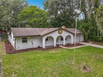 Charming single-story home boasts arched entryway, lush lawn, and mature trees at 2628 Vista Palm Dr, Edgewater, FL 32141