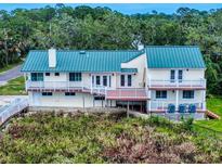 Stunning elevated exterior featuring a green roof, multiple balconies, and lush landscaping for privacy at 2950 Sunset Dr, New Smyrna Beach, FL 32168
