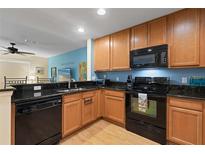 Well-equipped kitchen with wood cabinets, black appliances, and granite countertops at 511 Mount Olympus Blvd, New Smyrna Beach, FL 32168
