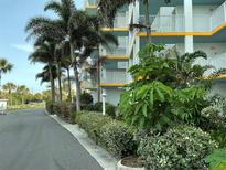 A condo building features balconies with white railings and blue ceilings, complemented by lush tropical landscaping at 5201 S Atlantic Ave # 407A, New Smyrna Beach, FL 32169
