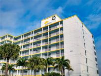 A multi-story condo complex with white walls, yellow trim, and palm trees in front of the building at 5201 S Atlantic Ave # 407A, New Smyrna Beach, FL 32169
