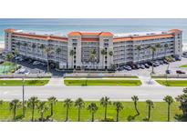Expansive beachfront condo building featuring a tennis court, palm trees, and covered parking at 5501 S Atlantic Ave # 4090, New Smyrna Beach, FL 32169