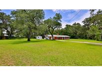 Charming single-story home with a brick facade, lush lawn, mature trees, and an exterior shed at 585 Corbin Park Rd, New Smyrna Beach, FL 32168