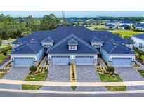 Stunning aerial view of townhomes with paved driveways, manicured landscaping and blue toned roofs at 6307 Hanfield Dr, Port Orange, FL 32128