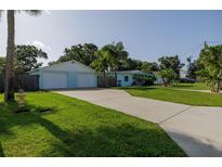 Charming exterior view of light blue home, showcasing a well-manicured lawn, driveway, and a two-car garage at 653 Goodwin Ave, New Smyrna Beach, FL 32169
