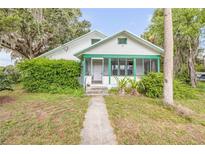 Charming home featuring a screened front porch and lush green landscaping at 102 N Brooks Cir, Oak Hill, FL 32759