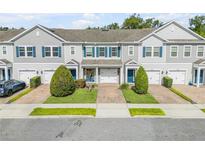 Charming townhomes featuring gray siding, blue shutters, well-manicured lawns, and individual garages at 1453 River Rock Ct, Oviedo, FL 32765
