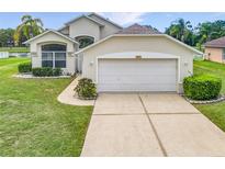 Well-maintained single-Gathering home with a two-car garage, complemented by lush landscaping and a green lawn at 1809 Forough Cir, Port Orange, FL 32128
