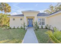 Inviting single-story home with a blue front door, manicured lawn, and lush landscaping at 1929 Pioneer Trl, New Smyrna Beach, FL 32168