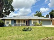 Charming single-story home with a well-manicured lawn, blue siding, and an attached garage at 2918 Mango Tree Dr, Edgewater, FL 32141