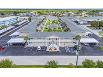 Aerial view of waterfront condo building with lush landscaping, boat docks, and ample parking at 335 N Causeway # E3, New Smyrna Beach, FL 32169