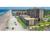 Stunning aerial view of a beachside resort with a pool, tennis court and direct beach access at 4139 S Atlantic Ave # B508, New Smyrna Beach, FL 32169