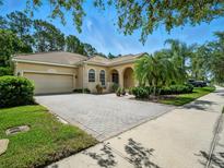 Charming home featuring a barrel tile roof, arched entryway, and a paver driveway, complemented by lush landscaping at 461 Luna Bella Ln, New Smyrna Beach, FL 32168