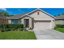 Charming home featuring a well-maintained lawn, inviting entrance, and a two-car garage under a sunny, blue sky at 518 Safe Harbor Dr, Edgewater, FL 32141